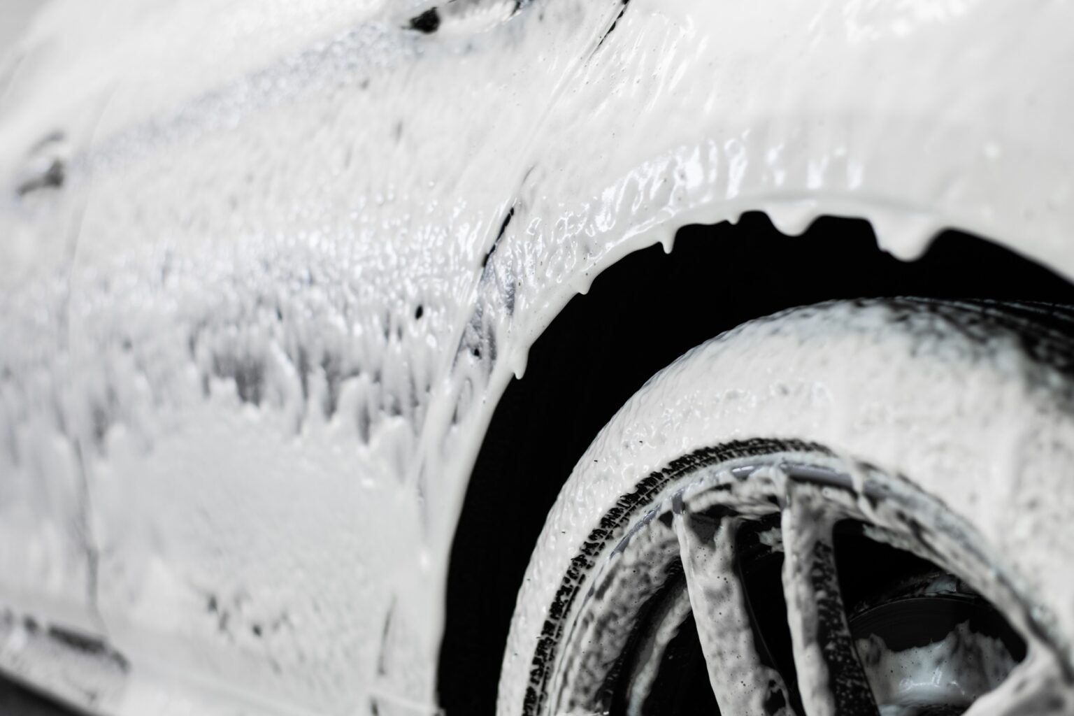 Car wash. The car thresholds is covered with white flowing foam at a carwash